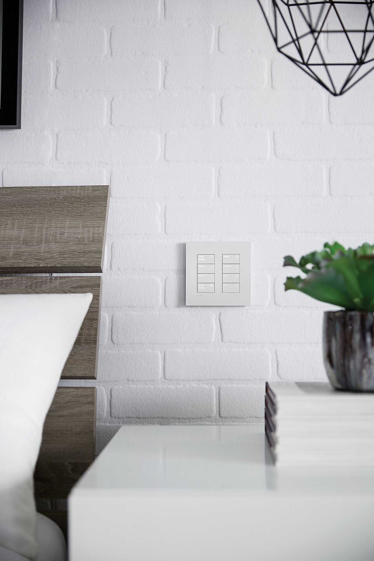 Two Lutron 4-button keypads in white side by side at a bedside wall