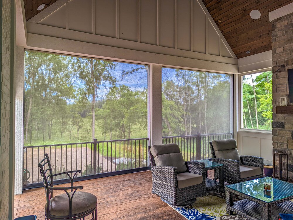 Covered porch with SunPro motorized solar screens lowered, keeping the view of the yard